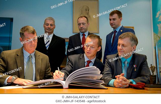 Expedition 49 NASA astronaut Shane Kimbrough, seated left, Russian cosmonauts Sergei Ryzhikov, seated center, and Andrey Borisenko of Roscosmos sign a guest...