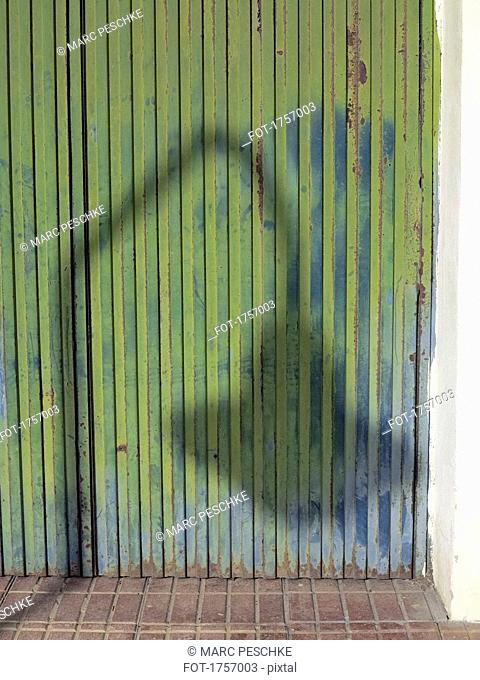Shadow of street light on rusty corrugated green iron