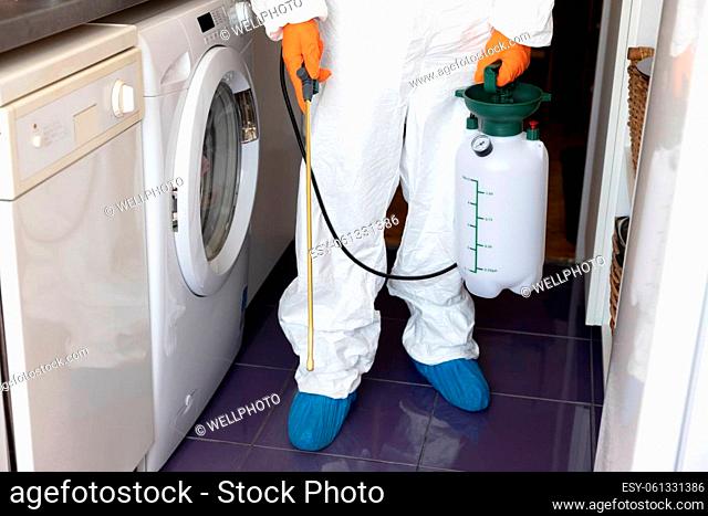 Pest control worker spraying insecticide with sprayer in the kitchen