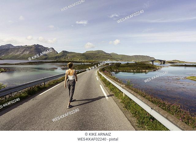 Young woman walking on an empty road, Lapland, Norway