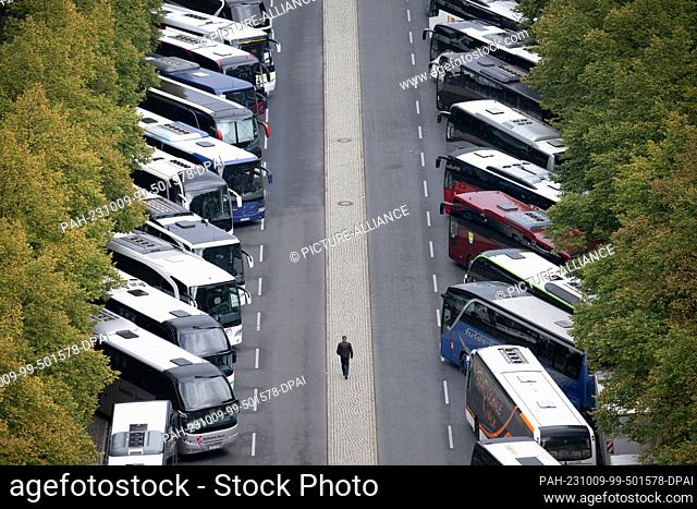 09 October 2023, Berlin: A man walks between buses carrying demonstrators during a major Verdi rally on the amendment to the Postal Act