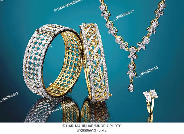 Diamond gold jewellery bracelet necklace and ring on green background