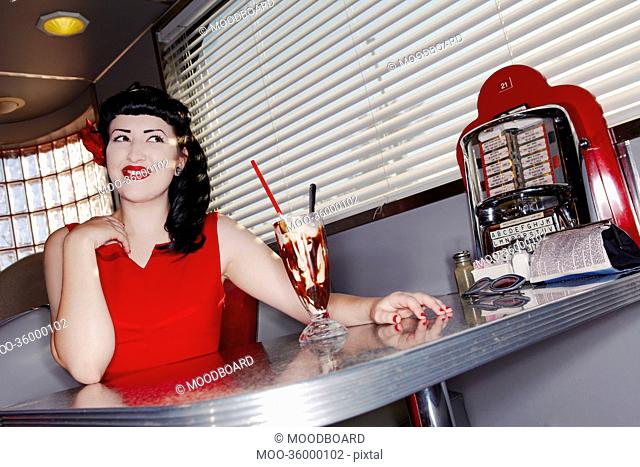 Young beautiful woman in red dress with chocolate smoothie at restaurant table