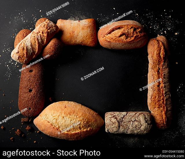 Top view of copy space on black wooden table with frame of different bread sorts. Baking and cooking concept background