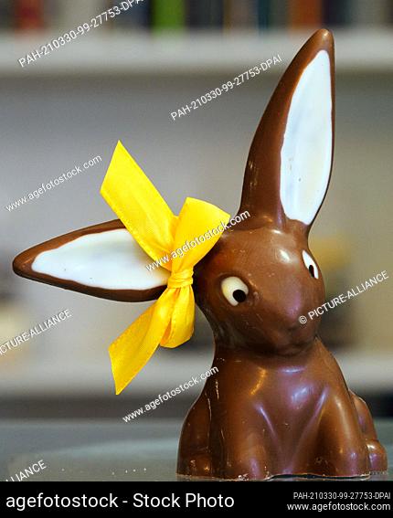 30 March 2021, Brandenburg, Himmelpfort: A pointy-eared Easter bunny made of milk chocolate stands on the sales counter in Sylke Wienold's chocolaterie