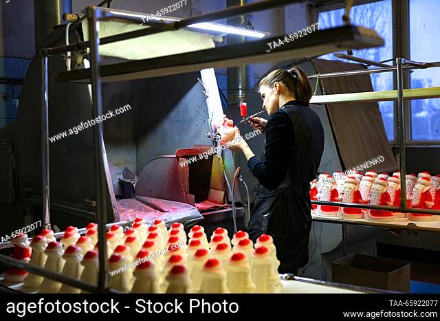 RUSSIA, VORONEZH - DECEMBER 19, 2023: An employee spray paints a Christmas ornament at the Igrushki factory. The enterprise is engaged in production of PVC...
