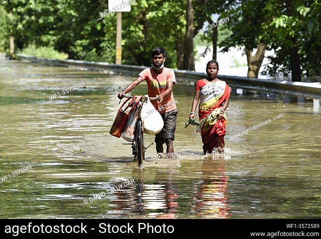Villagers waking wade through a flooded road, in Morigaon district of Assam, Monday, July 13, 2020