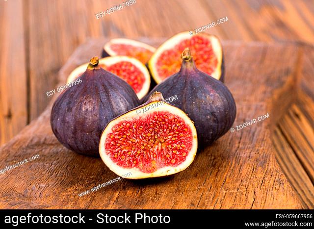 Group of whole and sliced ripe, delicious and sweets figs on a old rustic wooden cutting board
