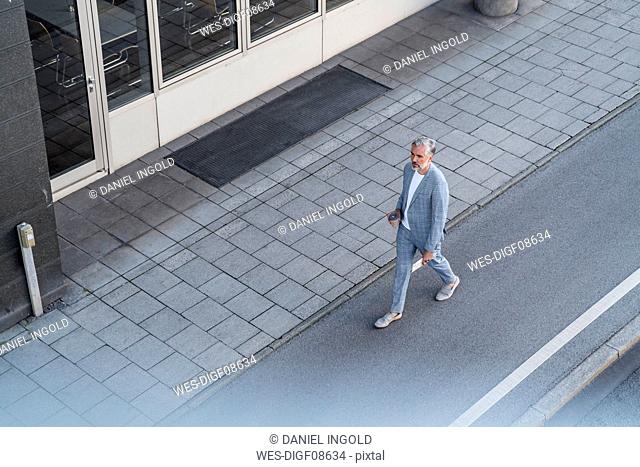 Top view of mature businessman walking on a road
