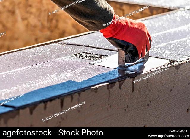 Construction Worker Using Hand Groover On Wet Cement Forming Coping Around New Pool