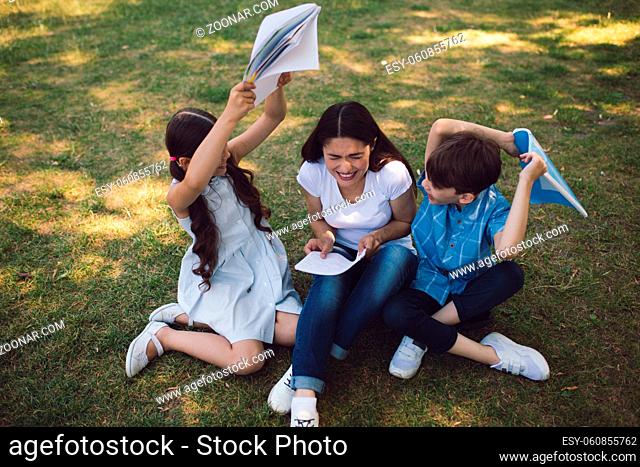 Children Are Fighting With Copy Books While Having Lesson In Park. Creative Lesson Concept