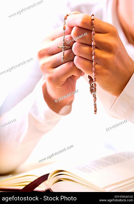 Christian believer praying to God with rosary in hand. Vertical version