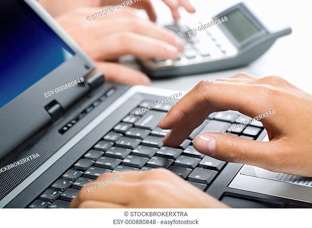 Hands typing a text on a laptop in a working environment