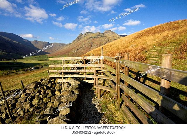 Footpath and stile with Great Langdale and the Langdale Pikes beyond, Lake District, Cumbria, England