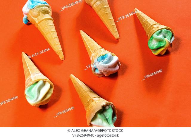 Sugar candy cones on an orange background, topped with frosted candy