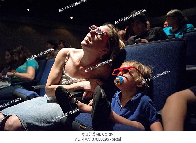 Mother and toddler son watching 3-D movie in theater
