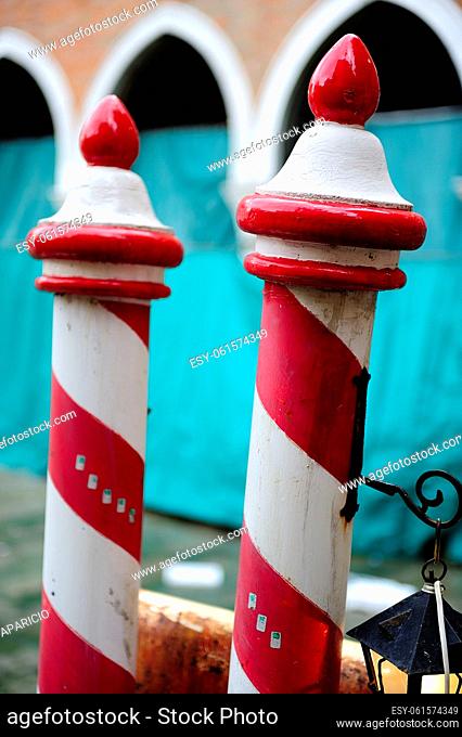 Typical mooring boats poles of red and white next to the Rialto Market in Venice