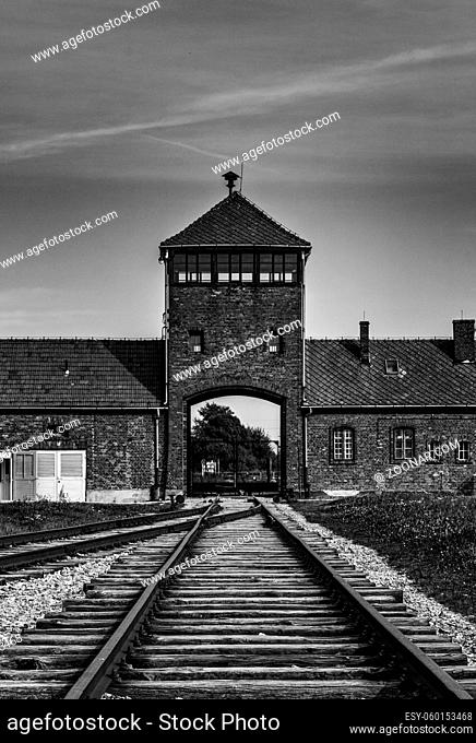 Auschwitz, Poland - 15 September, 2021: black and white view of the gatehouse and train tracks at Auschwitz Concentration Camp in Poland