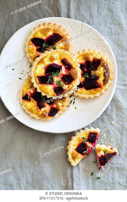 Mini quiches with beetroot and thyme on a white plate