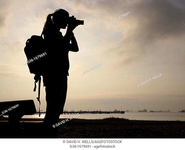 A photographer at sunrise in the East Beach area of Singapore