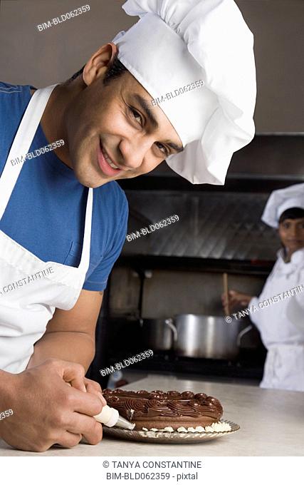Hispanic male pastry chef decorating cake