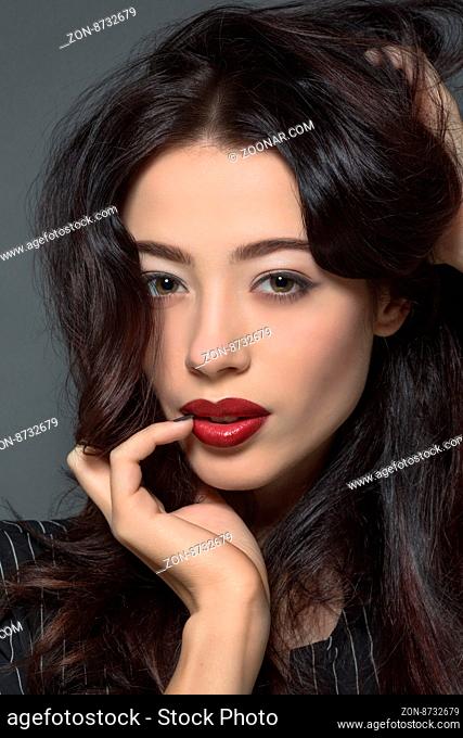 Fashion photo. Studio shot. Close-up portrait of fashion model woman with dark red lips posing for photographer in studio