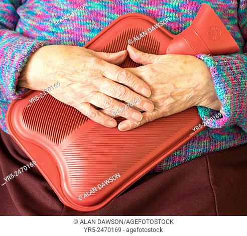 Elderly woman holding hot water bottle. England, UK