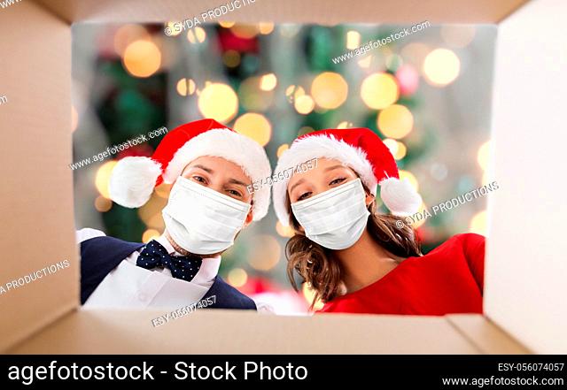 couple in medical masks opening christmas gift box