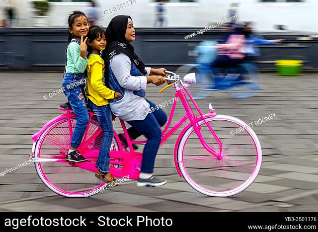 An Indonesian Family Cycling In Taman Fatahillah Square, Jakarta, Indonesia