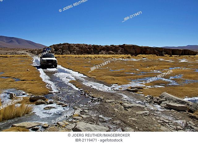 Off-road vehicle driving through an icy ford, Altiplano, Potosi, southern Bolivia, South America