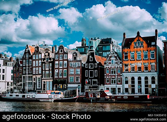 Wonderful architecture of Amsterdam. White fluffy clouds over Leaning Houses Amsterdam, Netherlands