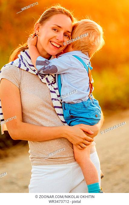 Happy woman and child having fun outdoors. Family lifestyle rural scene of mother and son in sunset sunlight