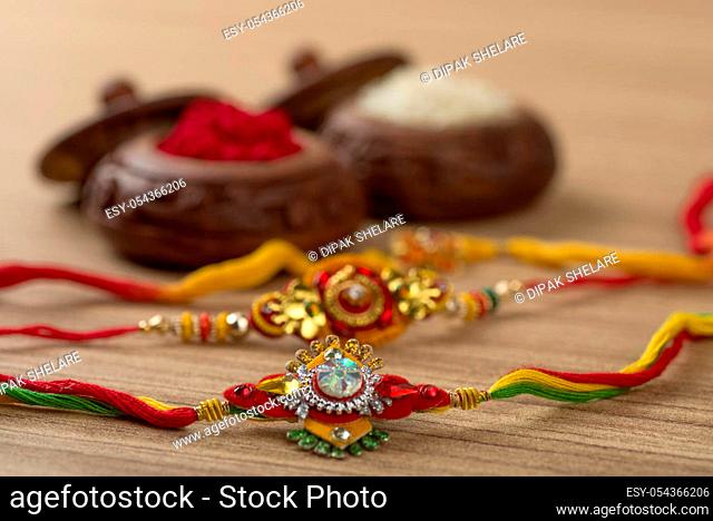 Indian festival: Raksha Bandhan background with an elegant Rakhi, Rice Grains and Kumkum. A traditional Indian wrist band which is a symbol of love between...