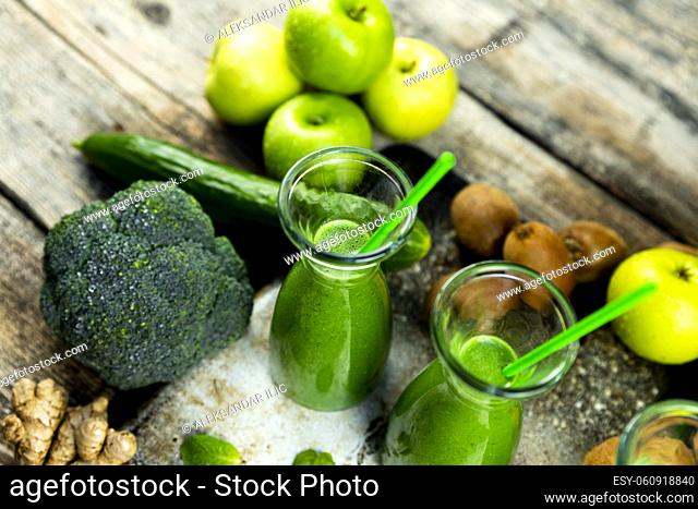 Healthy green smoothies with spinach, apple, kiwi, broccoli and mint in glass jar with fruits and vegetables on the wooden table