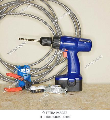 Cordless drill next to wire cutters and cable