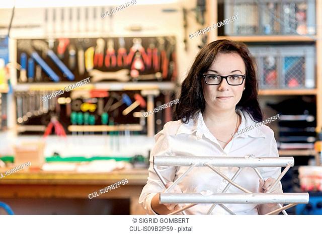 Woman in bicycle repair shop holding bicycle part