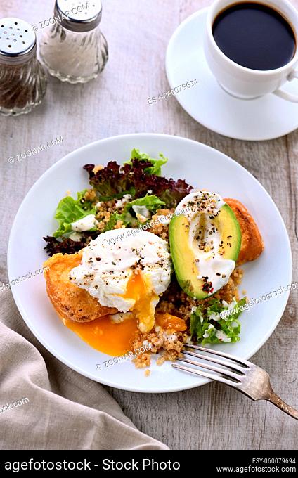 A healthy and balanced breakfast plate. Benedict's egg spreads on a toasted toast with half an avocado, quinoa and lettuce, seasoned  spices and yogurt dressing