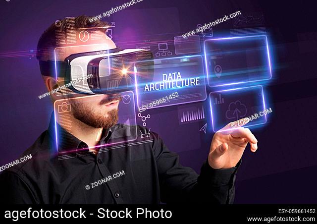 Businessman looking through Virtual Reality glasses with DATA ARCHITECTURE inscription, new technology concept