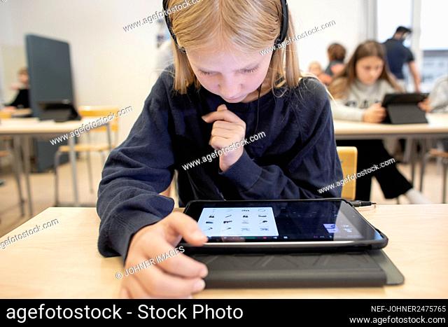 Girl in classroom using digital tablet