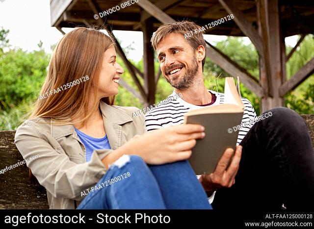 Couple sitting with book on bench