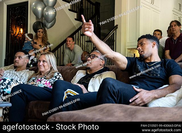 30 April 2021, US, Lake Forest: Amon-Ra St. Brown (2nd from right) sits on a couch between his mother Miriam Brown and brother Equanimeous St