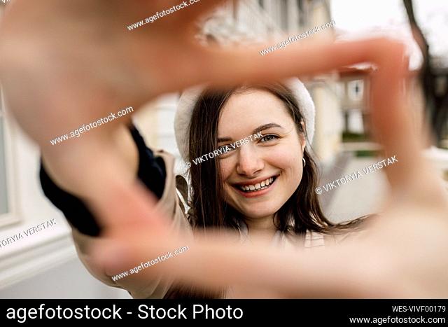 Happy young woman making finger frame