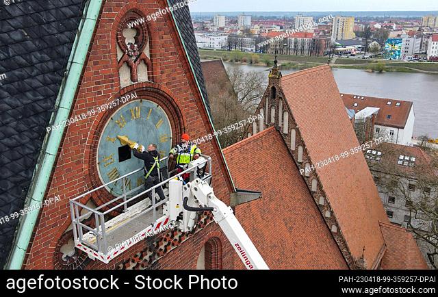 18 April 2023, Brandenburg, Frankfurt (Oder): An employee (l) from the company Bittner Glocken- und Turmuhren and a technician from the lifting platform mount...