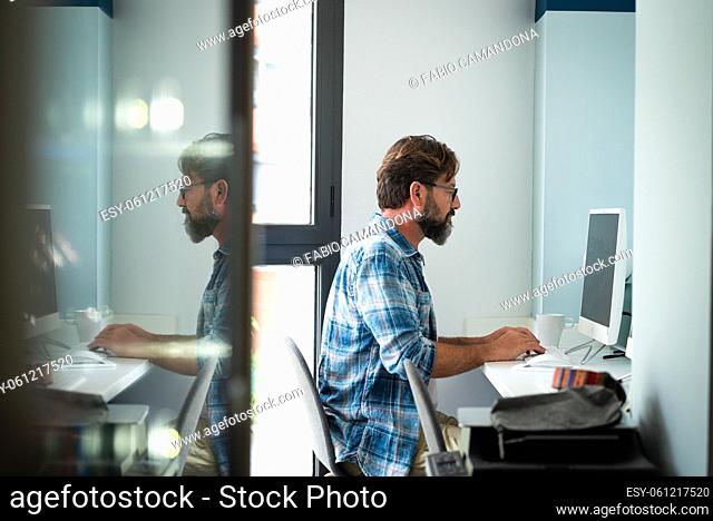 Caucasian freelance people man sitting at the desk typing on desktop computer for online job internet connected lifestyle - hipster adult male working at home...