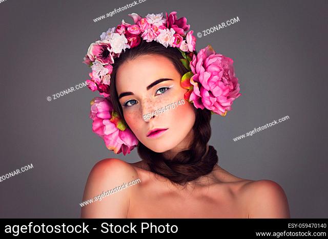 Beautiful brunette young woman with braids and pink floral headphones head accessory over pink background. Copy space