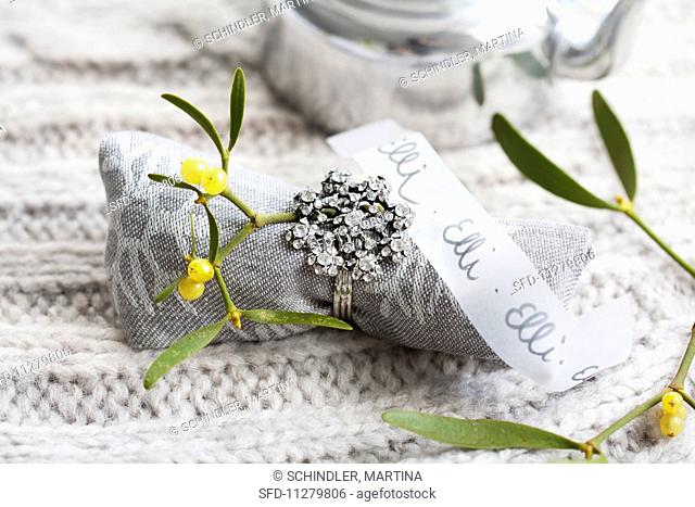A linen napkin decorated with a sprig of mistletoe and a ring with a transparent paper strip as a name tag