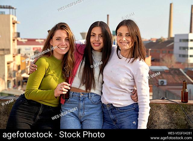 Beautiful women standing with arms around on rooftop