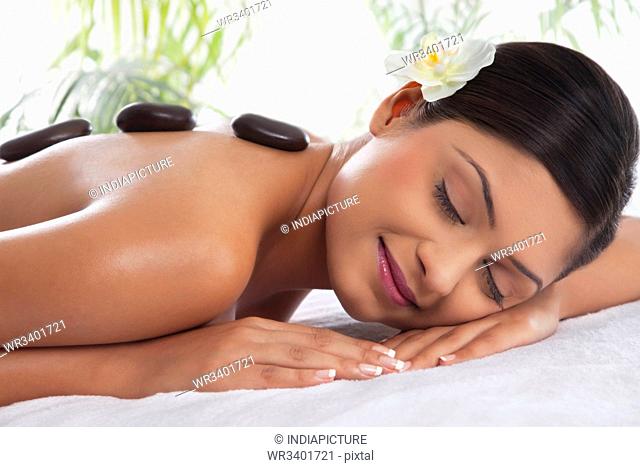 Smiling young woman getting lastone treatment