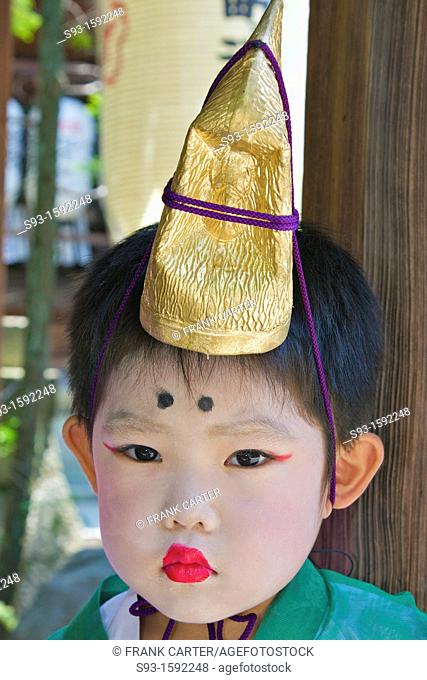 A small costumed boy with make-up, taking part in a temple celebration