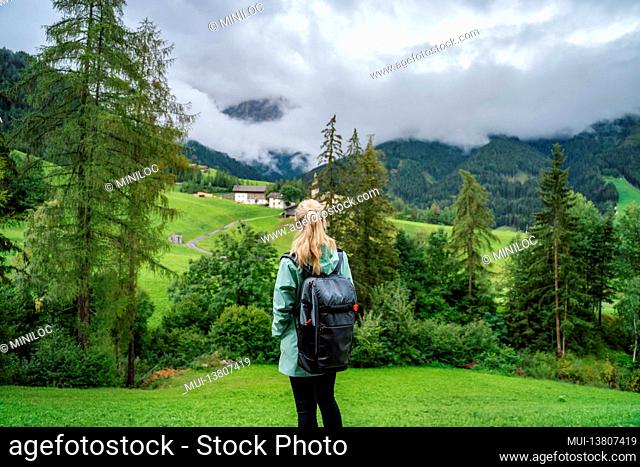 Woman enjoy the view of Val di Funes valley in the Dolomites, Santa Maddalena touristic village, Dolomites, Italy, Europe